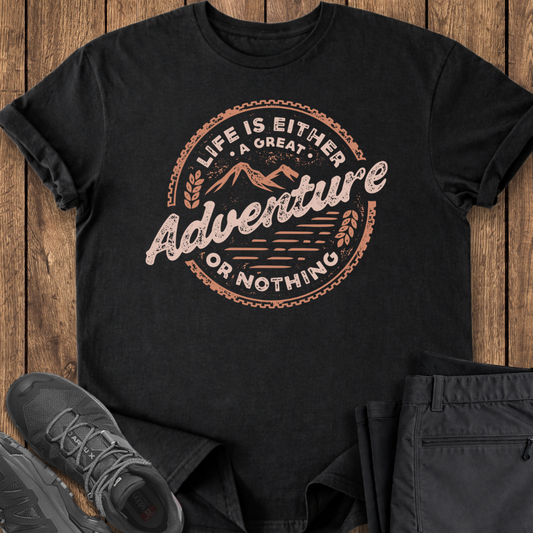 Black t-shirt with 'Life is Either a Great Adventure or Nothing' design on a wooden surface with shoes and pants.