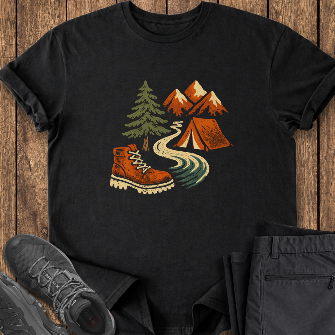 Black t-shirt with outdoor design featuring a boot, tent, and mountains on a wooden surface.