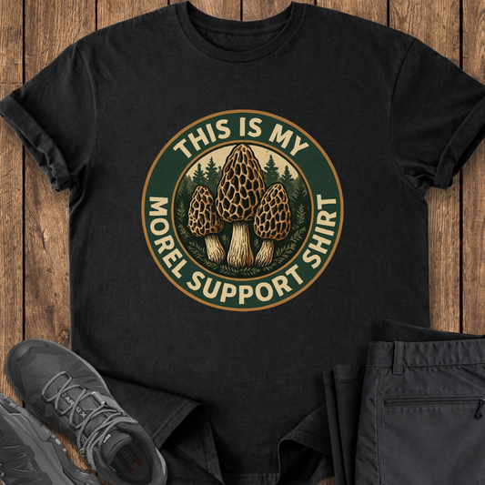 Black t-shirt with mushroom graphic and text on a wooden surface