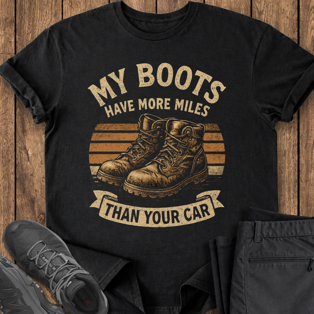 Black t-shirt with boots graphic and text on a wooden surface