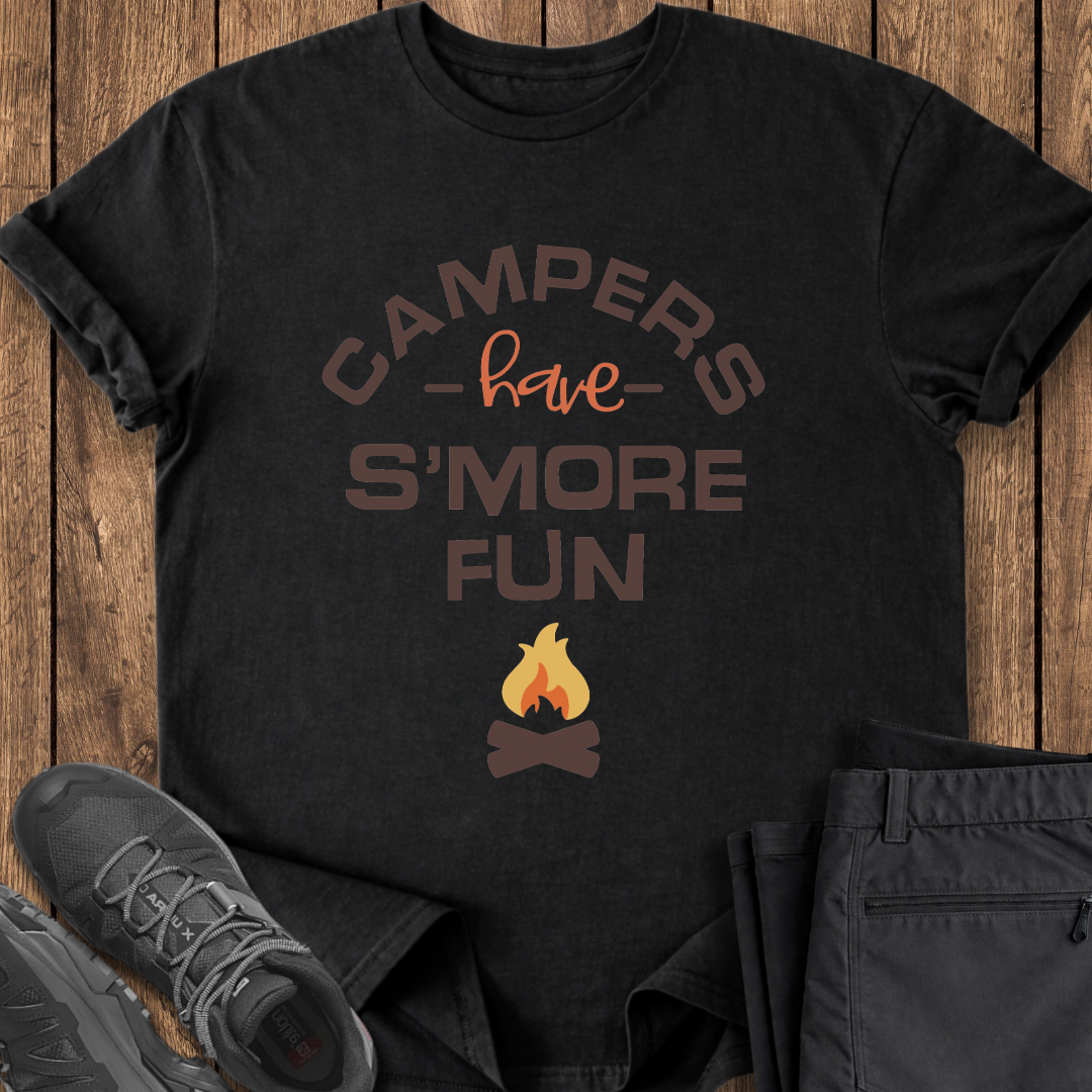 Black t-shirt with 'Campers have S'more Fun' text and campfire graphic on a wooden surface with shoes and pants.