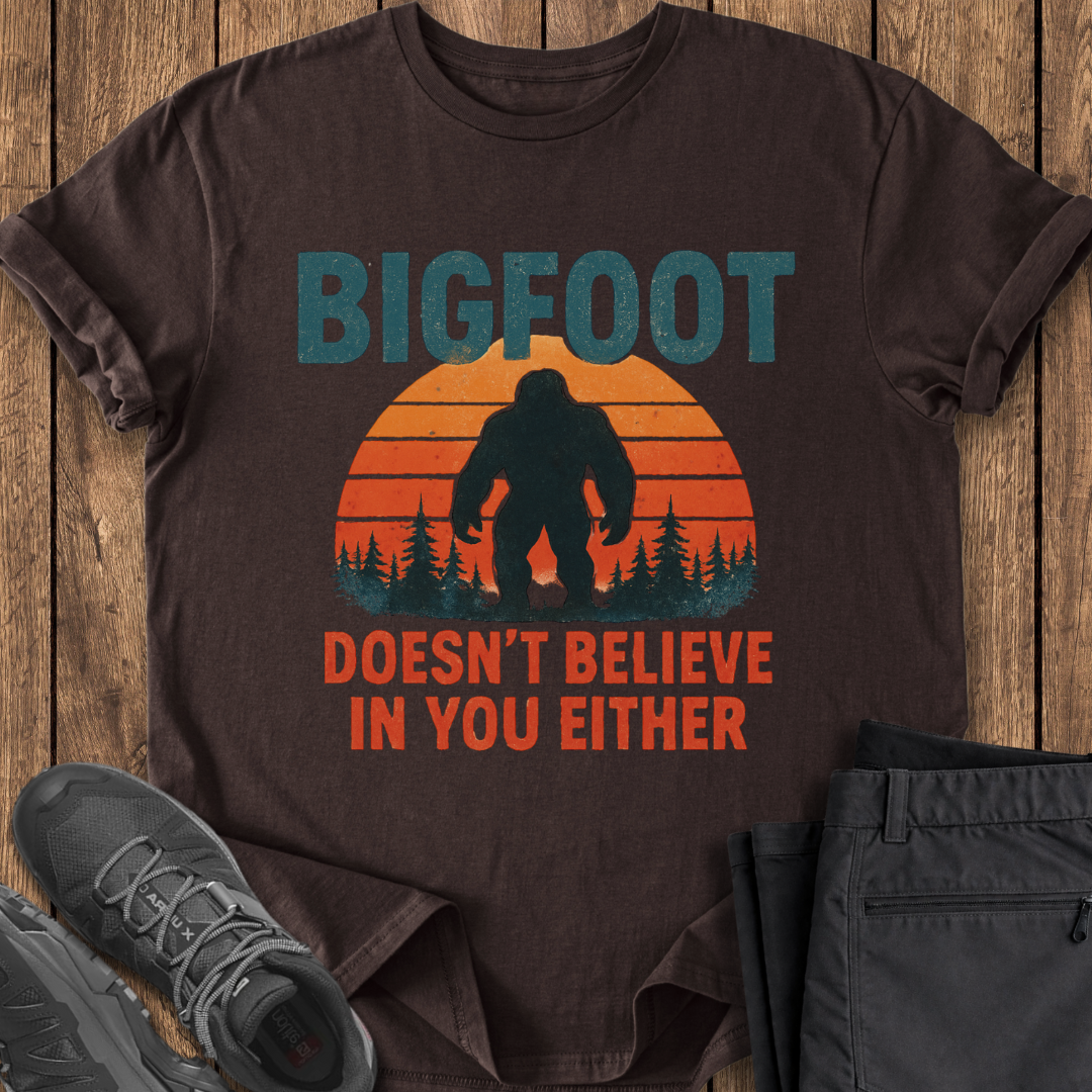 Brown t-shirt with Bigfoot graphic and text on a wooden surface