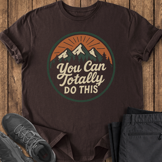 Brown t-shirt with motivational quote on a wooden surface with shoes and pants.