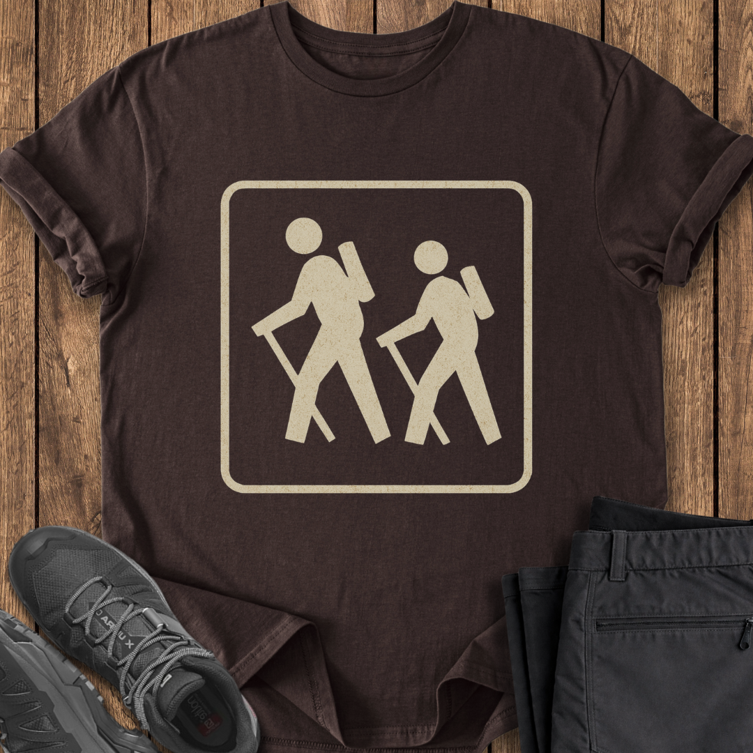 Brown t-shirt with hiking icon on a wooden surface with shoes and pants. vintage national park sign backpaking hiking t shirt