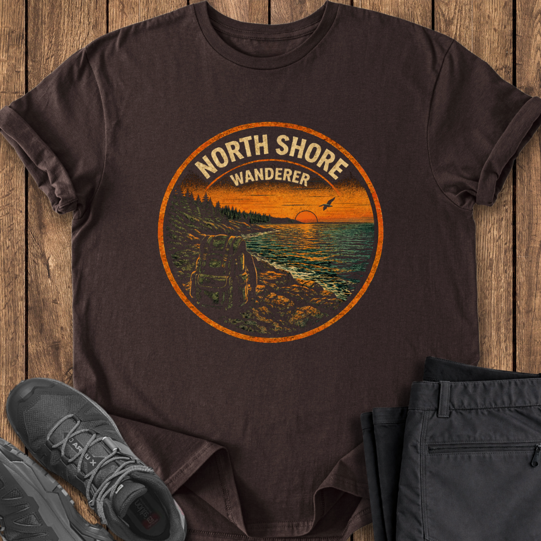 Brown t-shirt with 'North Shore Wanderer' graphic on a wooden surface with shoes and pants. north shore lake superior hiking trail