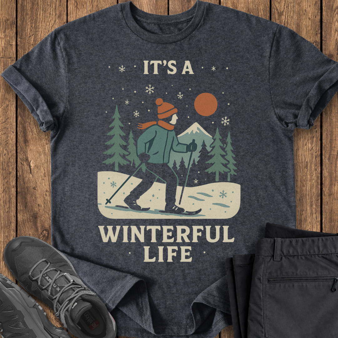 Dark gray t-shirt with winter-themed graphic and text 'It's a Winterful Life' on a wooden surface.