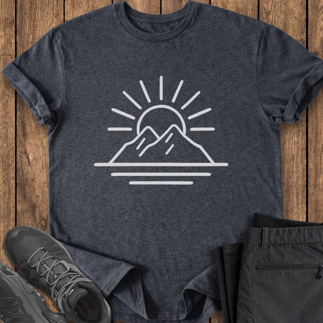 Dark gray t-shirt with mountain and sun design on a wooden surface, accompanied by black shoes and pants. minimalist mountain t shirt