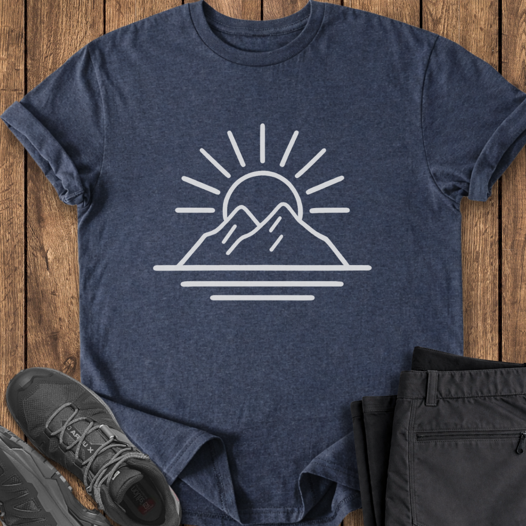Navy t-shirt with mountain and sun design on a wooden surface with shoes and pants.
