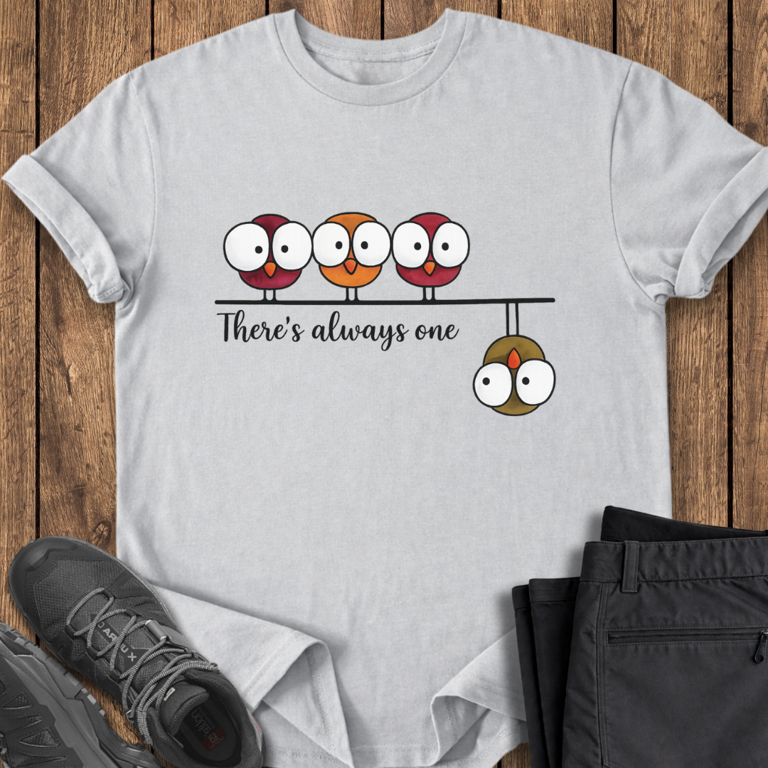 White t-shirt with cartoon design and text on a wooden surface with shoes and pants. funny birding hiking t shirt