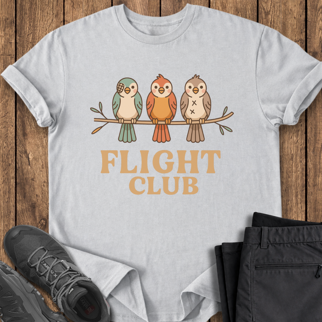 White t-shirt with 'FLIGHT CLUB' and bird design on a wooden surface with shoes and pants.