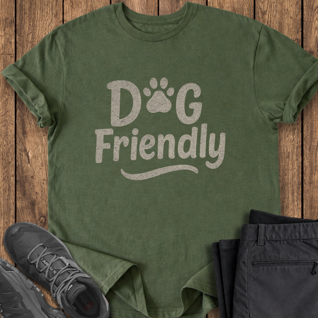 Green t-shirt with 'Dog Friendly' text on a wooden surface with shoes and pants.