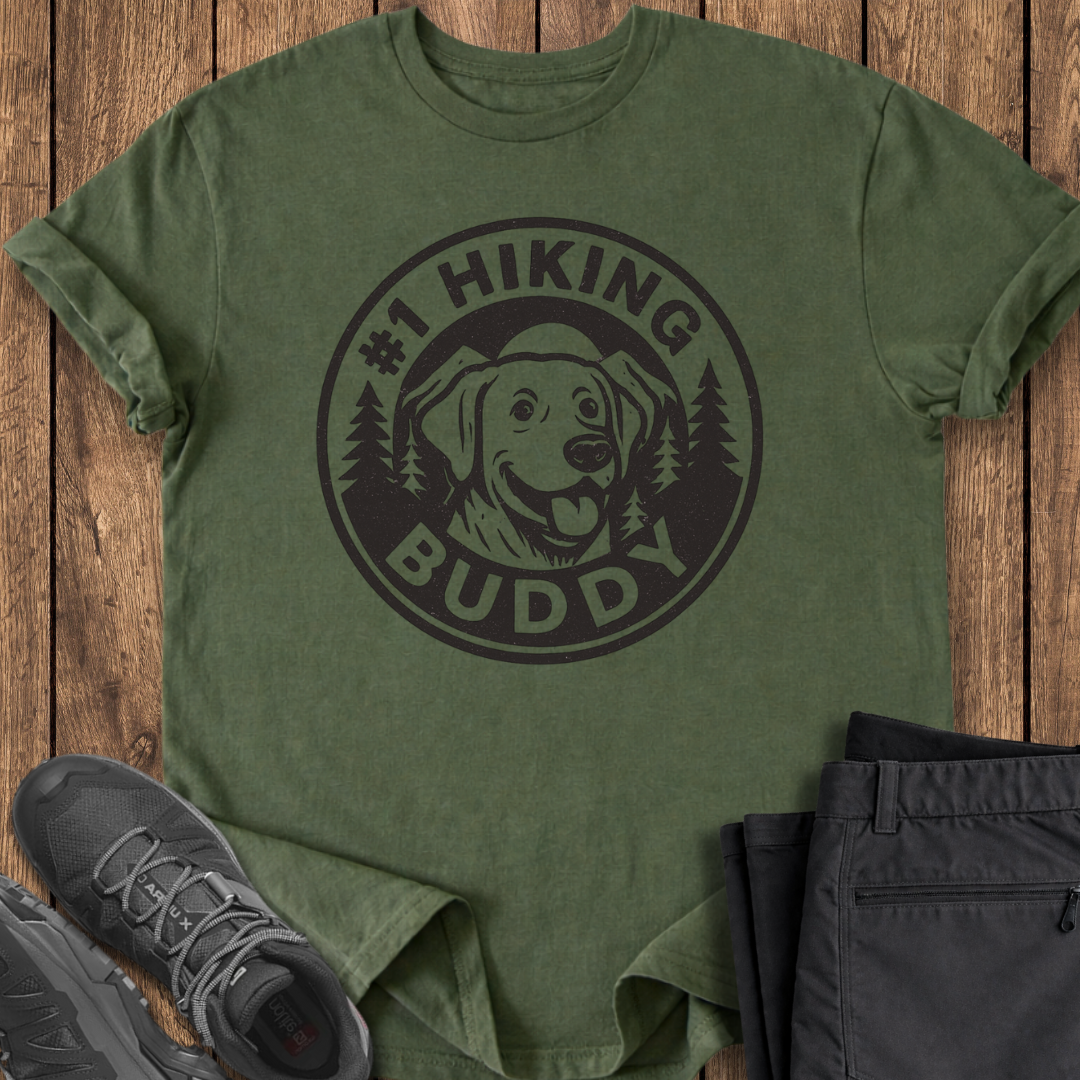 Green t-shirt with 'Hiking Buddy' design on a wooden surface with shoes and pants. hiking with dogs t shirt