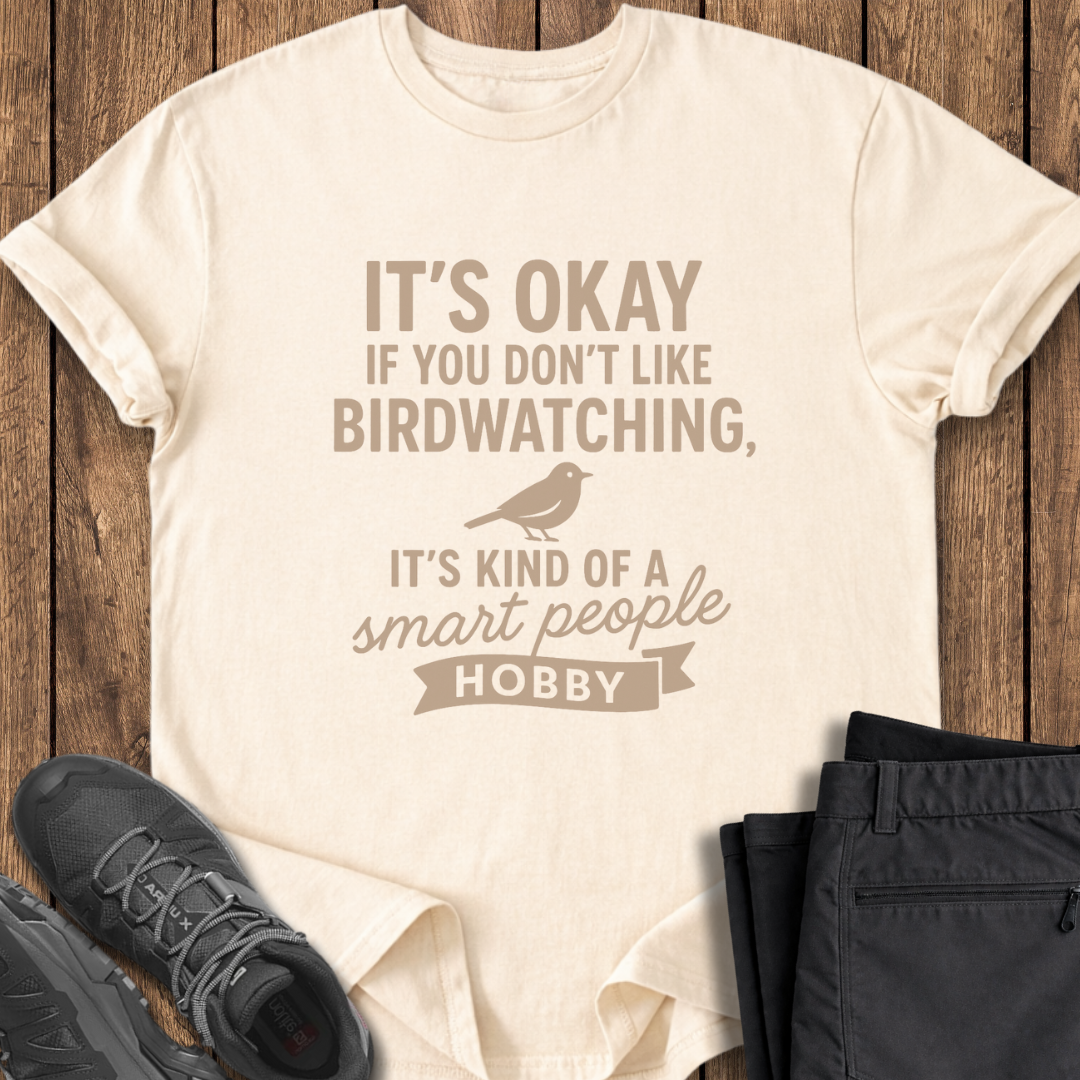 Beige t-shirt with humorous text design on a wooden surface with shoes and pants.