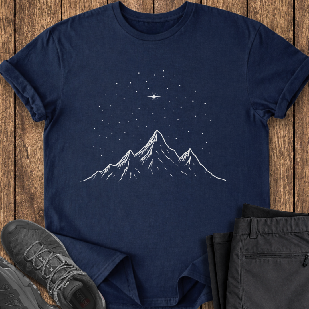 Navy blue t-shirt with mountain and star design on a wooden surface with shoes and pants.