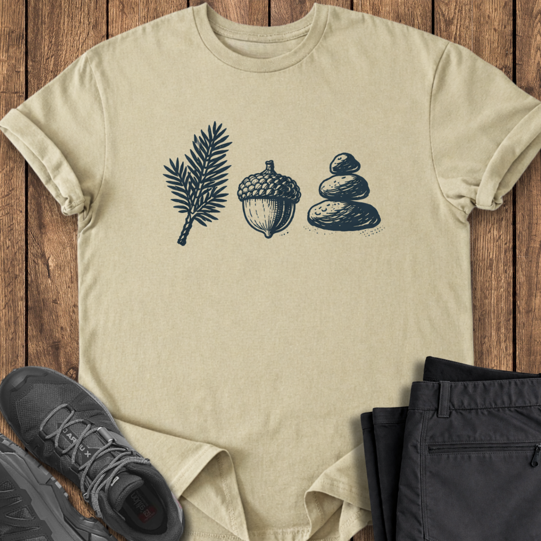 Beige t-shirt with nature-themed design on a wooden surface with shoes and pants. camping hiking tee
