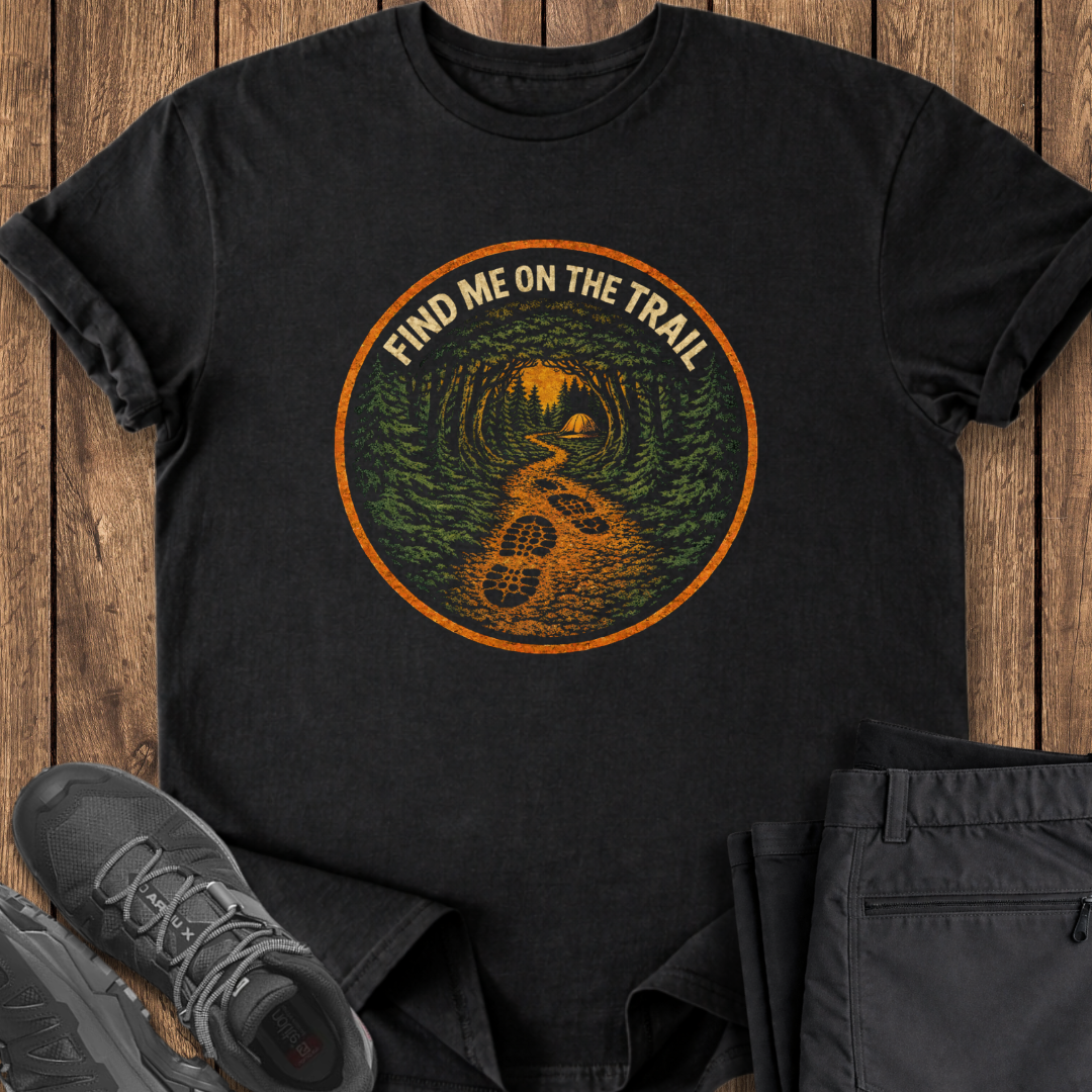 Black t-shirt with 'Find Me on the Trail' design on a wooden surface with shoes and pants. hiking t shirt