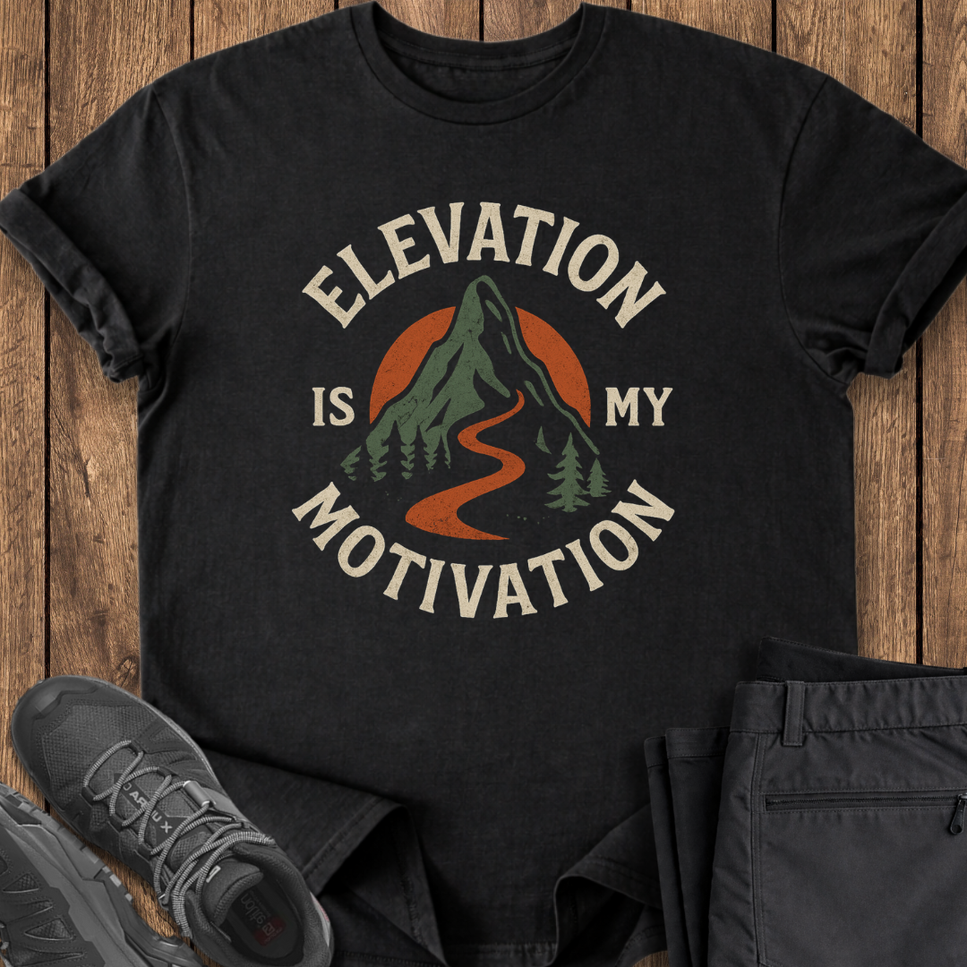 Black t-shirt with 'Elevation is my Motivation' graphic on a wooden surface with shoes and pants. hiking climbing adventure t shirt
