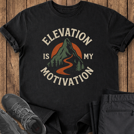 Black t-shirt with 'Elevation is my Motivation' graphic on a wooden surface with shoes and pants. hiking climbing adventure t shirt