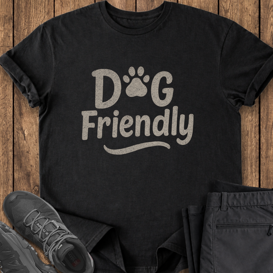 Black t-shirt with 'Dog Friendly' text on a wooden surface with shoes and pants.