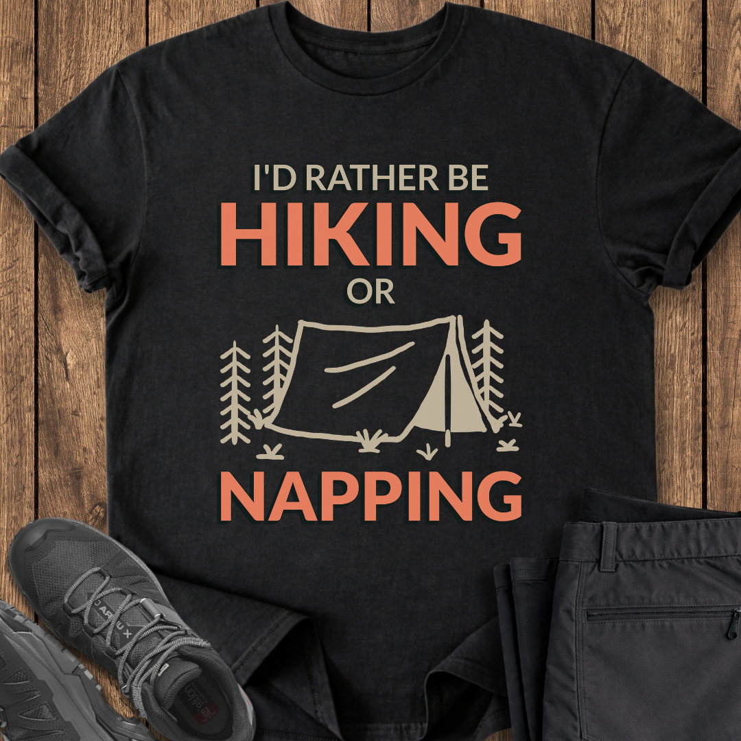 Black t-shirt with 'I'd Rather Be Hiking or Napping' text and camping graphic on a wooden surface. funny camping hiking t shirt