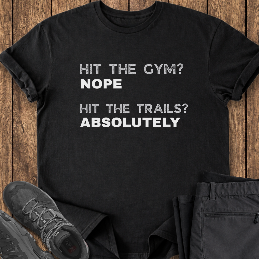 Black t-shirt with humorous text on a wooden surface with shoes and pants.