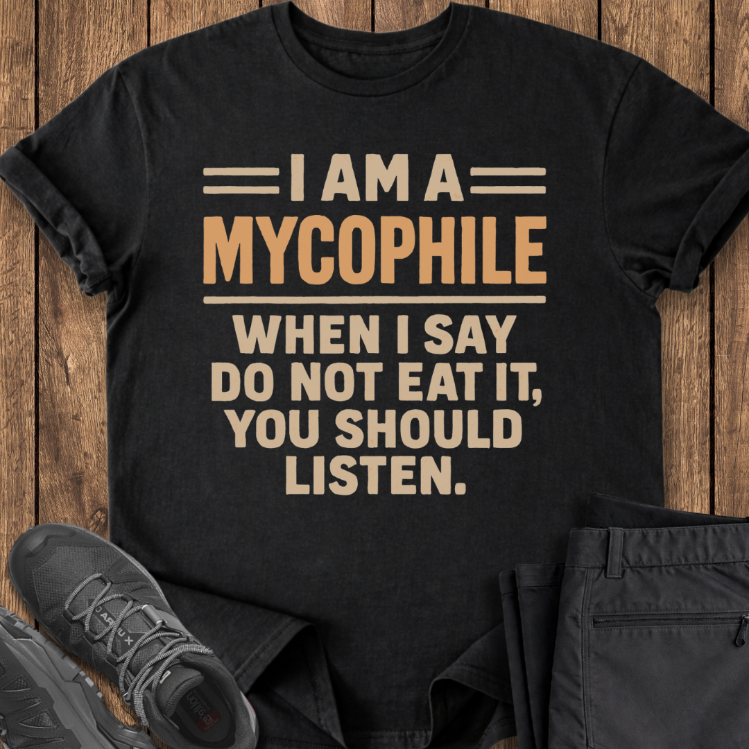 Black t-shirt with humorous text design on a wooden surface with shoes and pants.