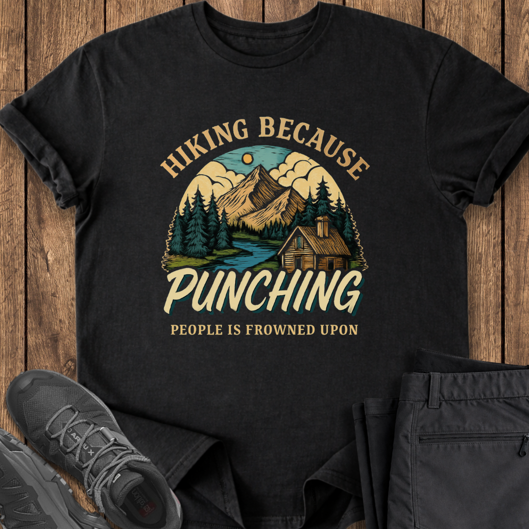 Black t-shirt with hiking graphic and text on a wooden surface with shoes and pants. funny hiking tshirt