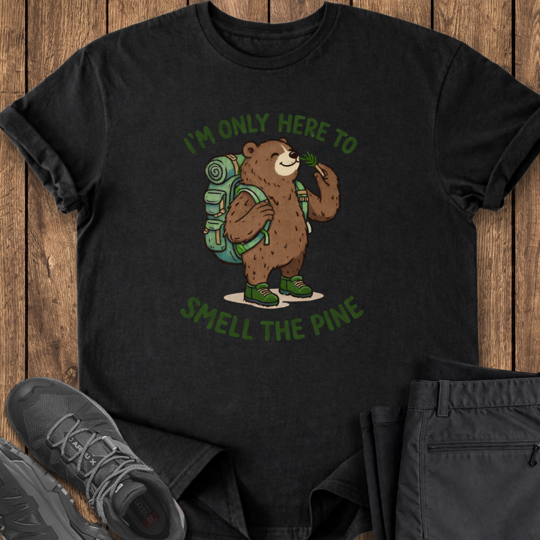 Black t-shirt with bear graphic and text 'I'm only here to smell the pine' on a wooden surface. funny backpacking hiking t shirt
