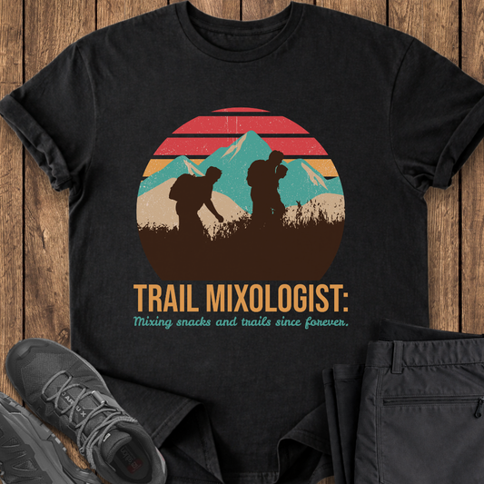 Black t-shirt with 'Trail Mixologist' graphic on a wooden surface with shoes and pants. mountain hiking funny t shirt