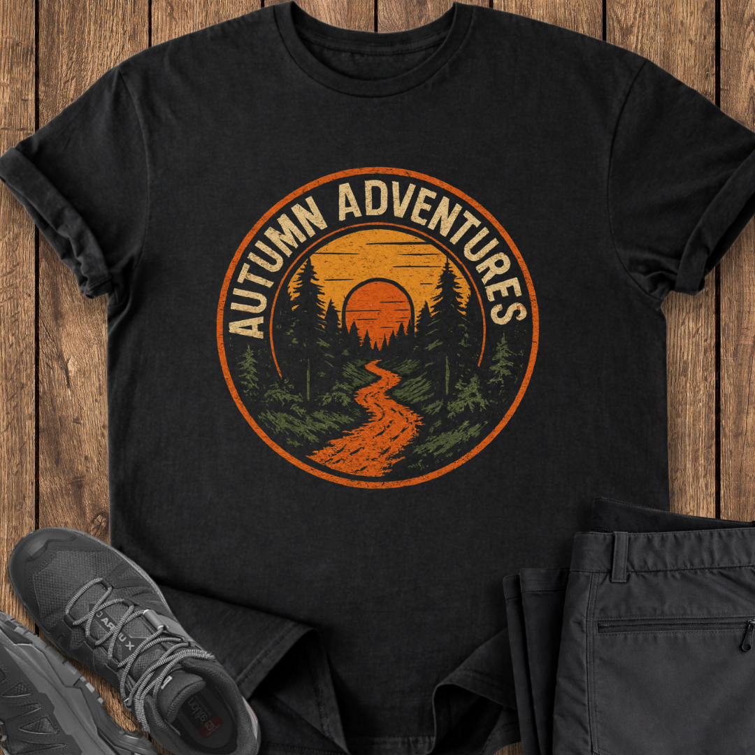 Black t-shirt with 'Autumn Adventures' design on a wooden surface with shoes and pants. hiking outdoor t shirt