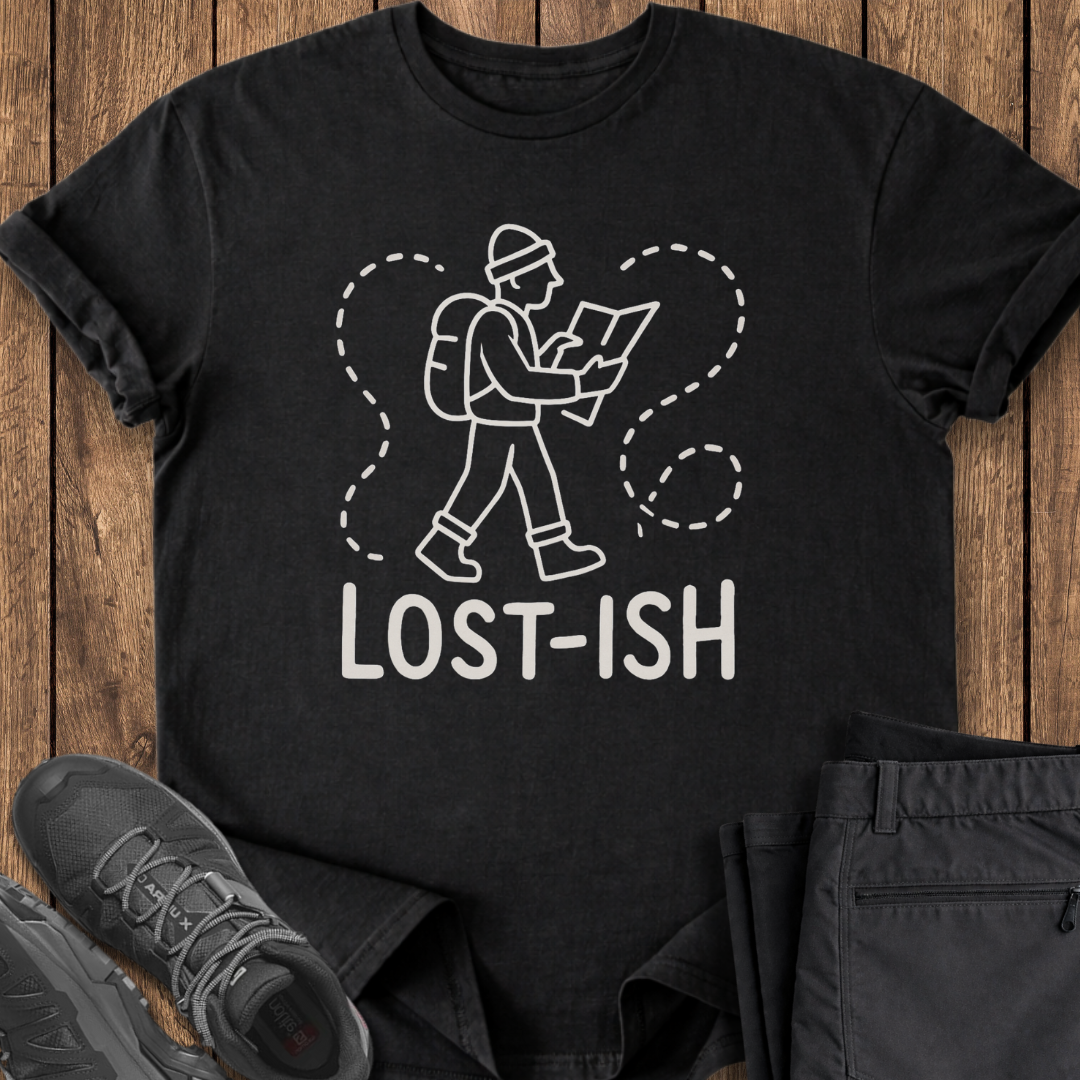 Black t-shirt with 'LOST-ISH' graphic on a wooden surface with shoes and pants.