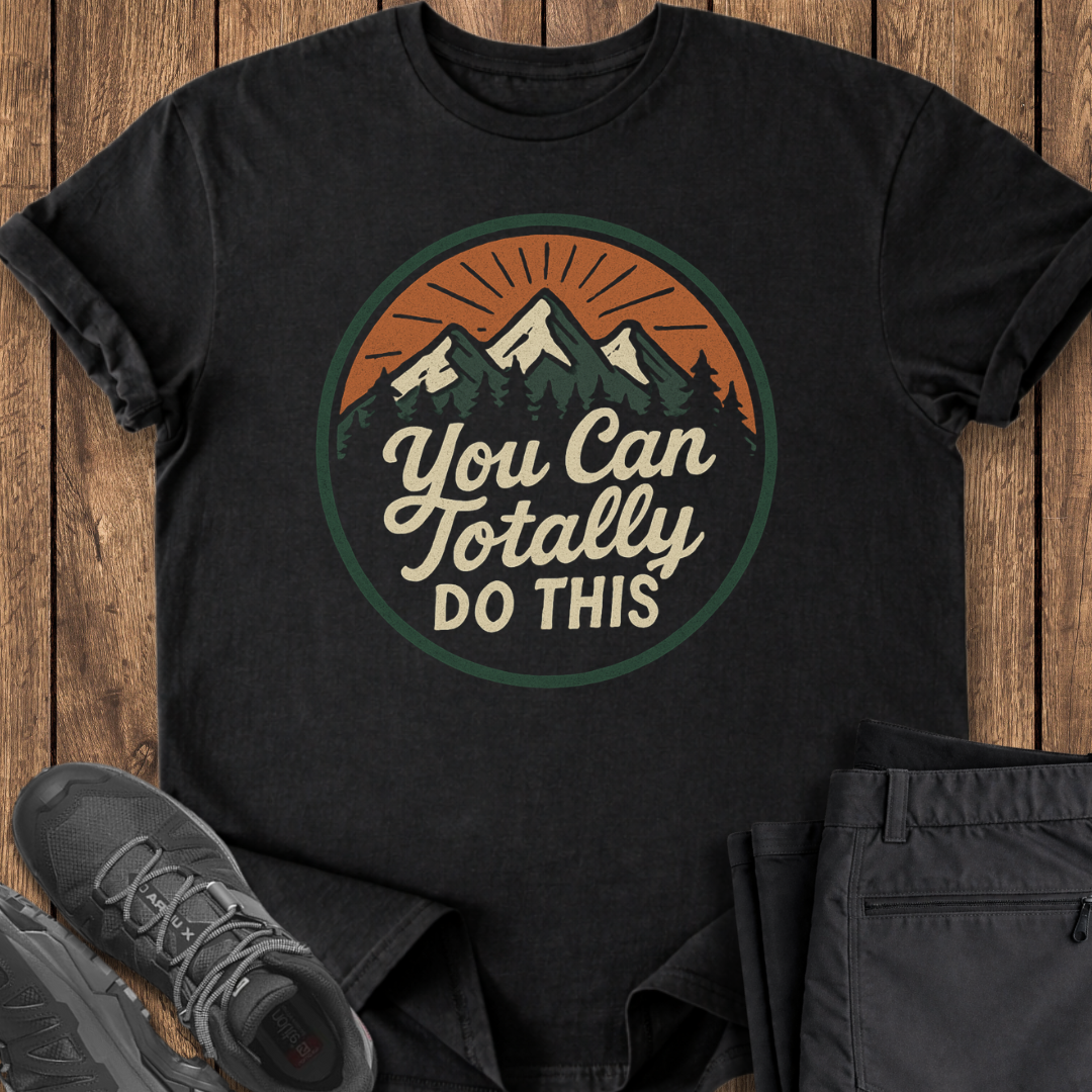 Black t-shirt with motivational quote on a wooden surface with shoes and pants.