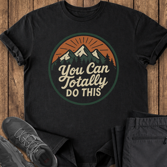 Black t-shirt with motivational quote on a wooden surface with shoes and pants.