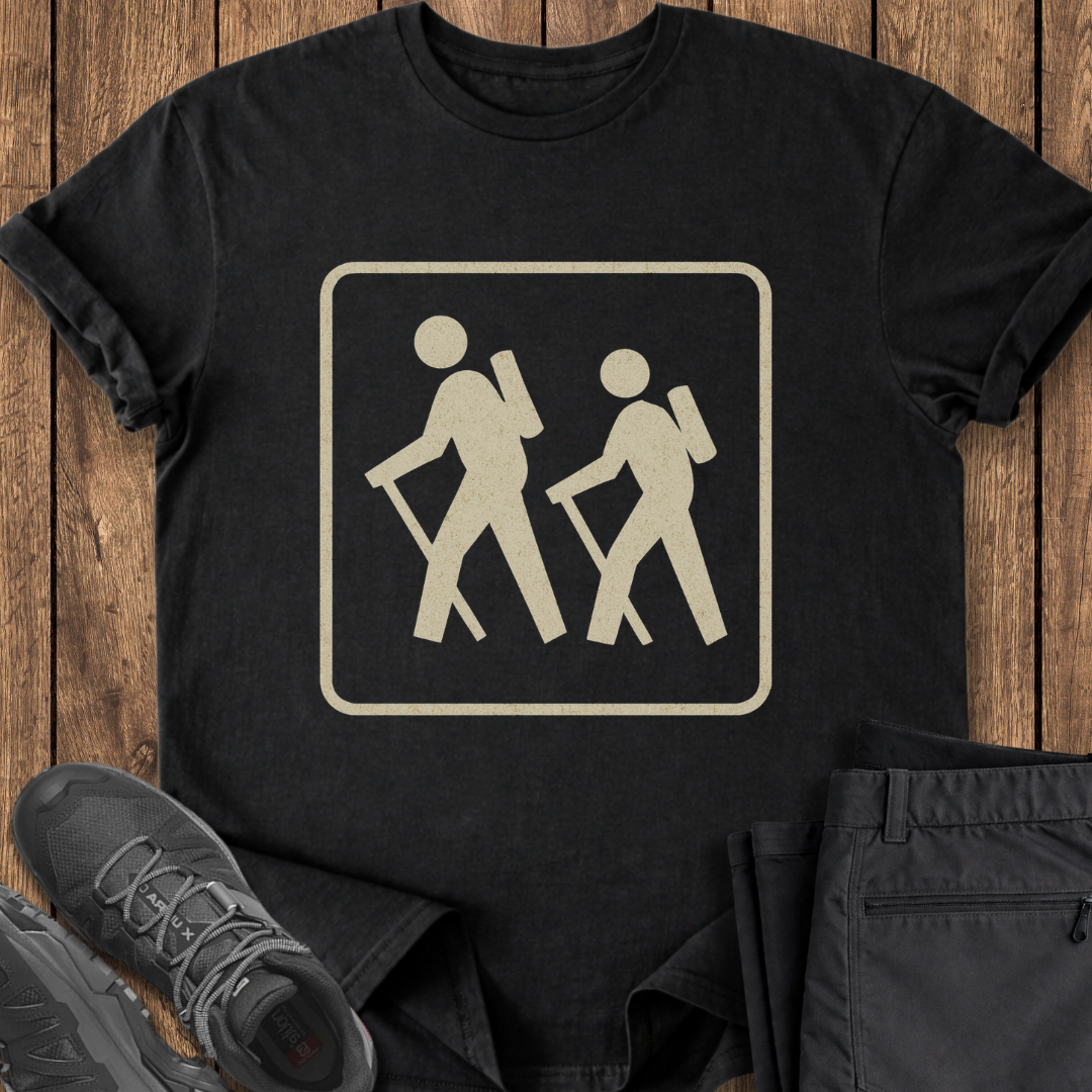 Black t-shirt with hiking symbol on a wooden surface with shoes and pants. vintage hiking trail national parks