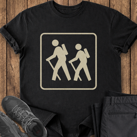Black t-shirt with hiking symbol on a wooden surface with shoes and pants. vintage hiking trail national parks