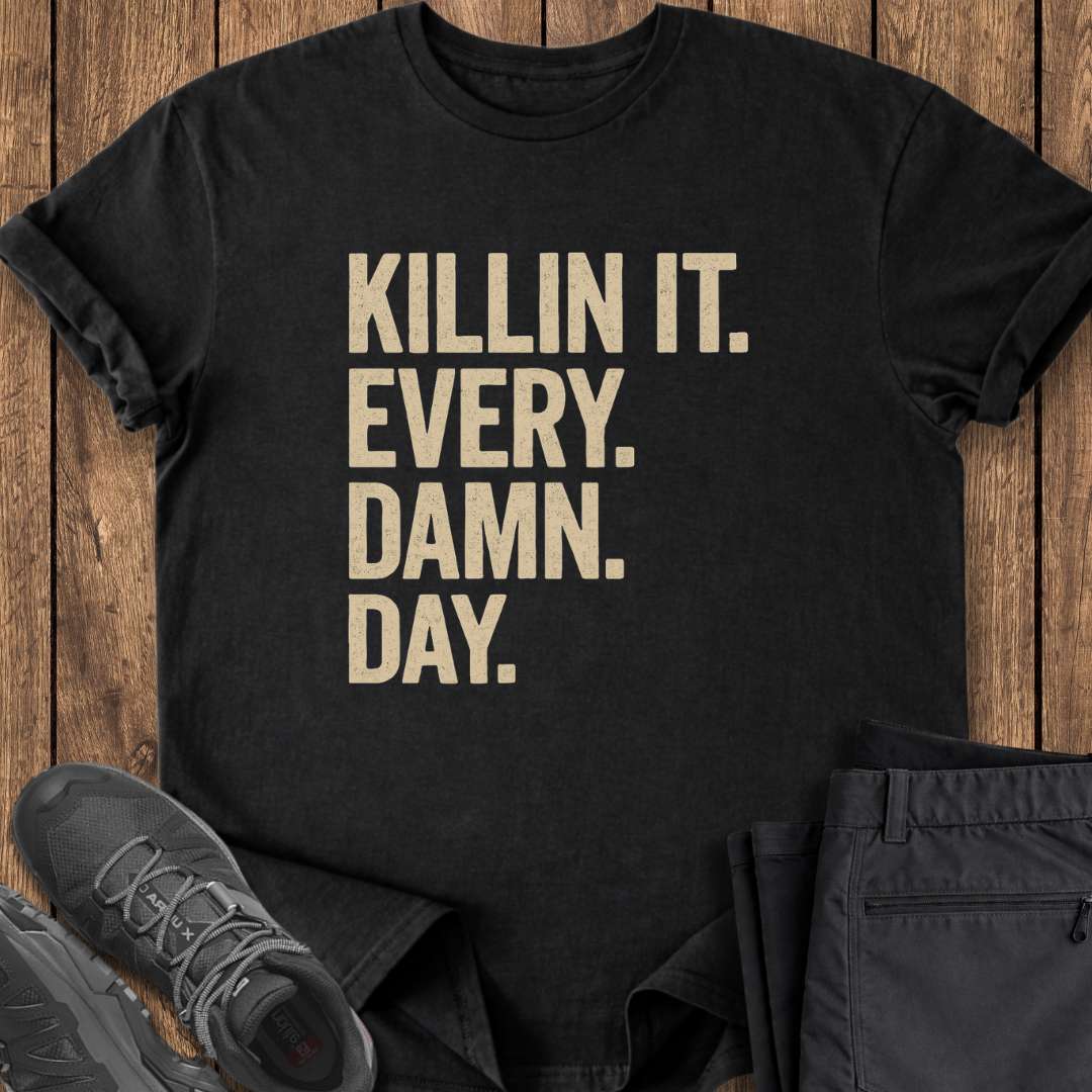 Black t-shirt with 'KILLIN IT. EVERY. DAMN. DAY.' text on a wooden surface with shoes and pants.