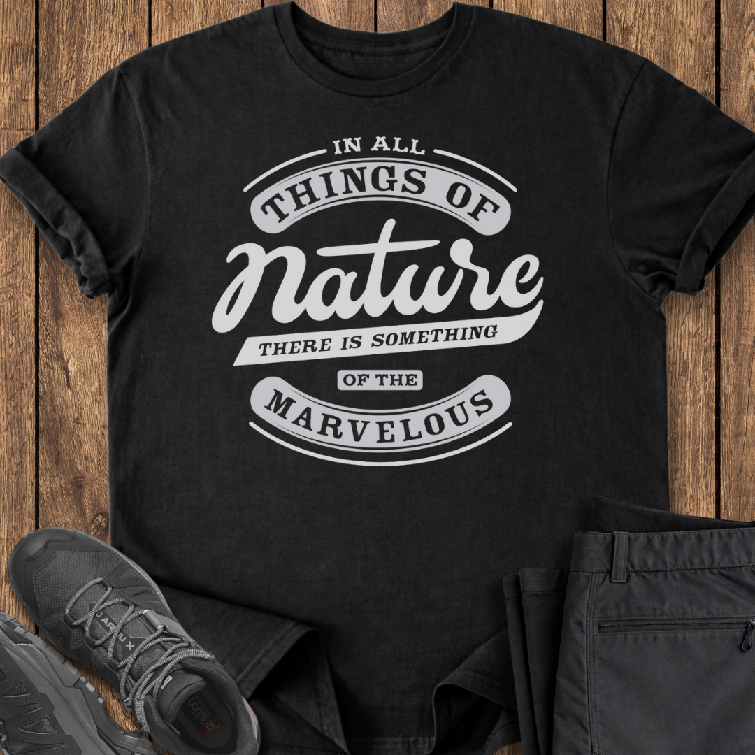Black t-shirt with white text on a wooden surface with shoes and pants.