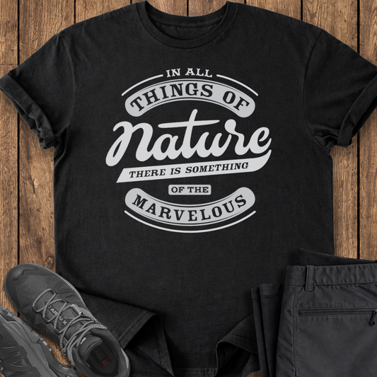 Black t-shirt with white text on a wooden surface with shoes and pants.