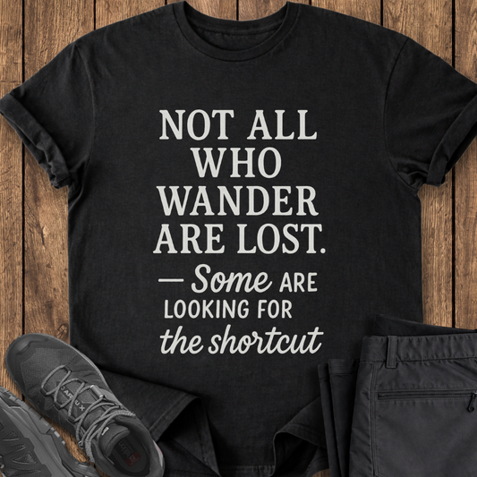 Black t-shirt with motivational quote on a wooden surface with shoes and pants. funny hiker shirt