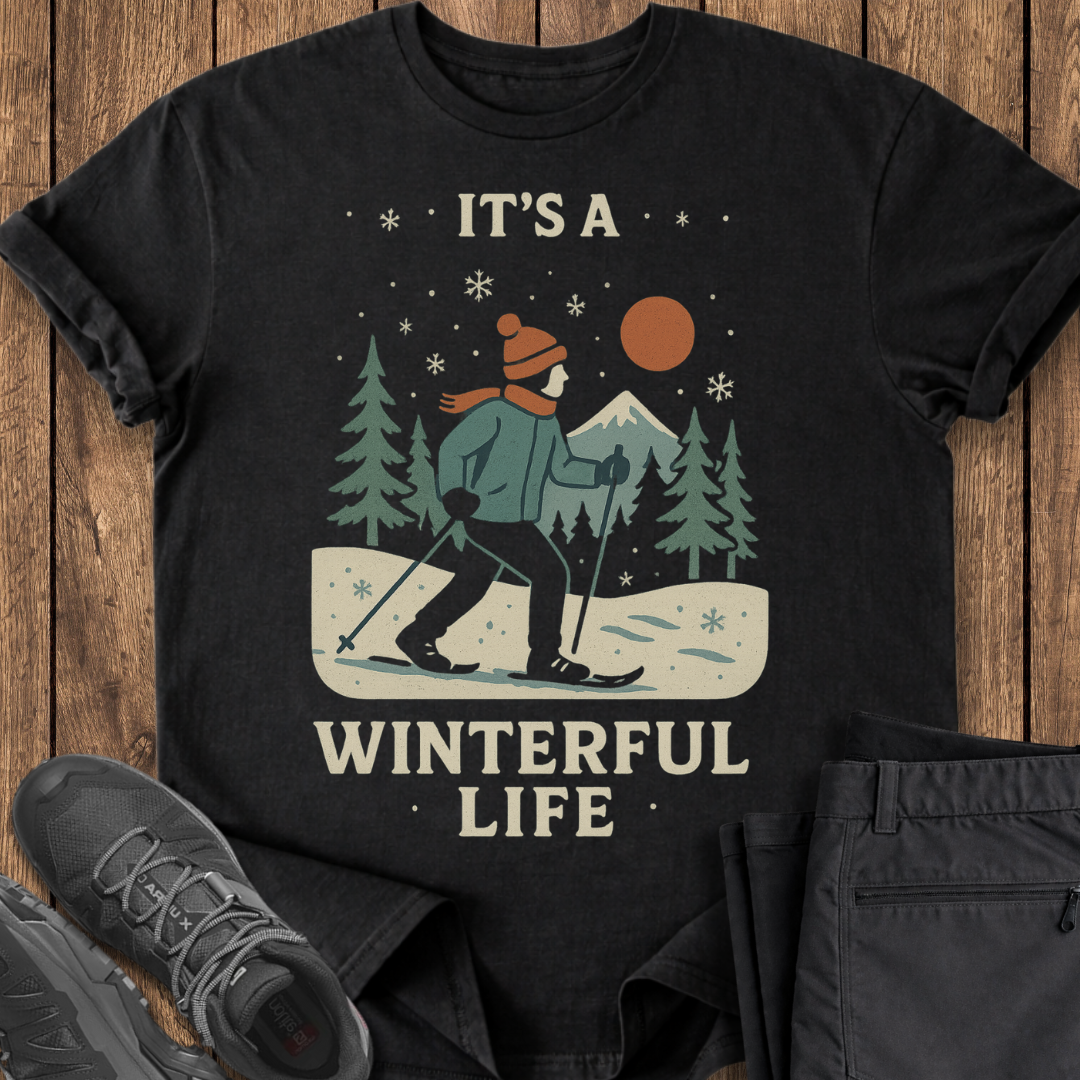 Black t-shirt with a winter-themed graphic and text on a wooden surface.