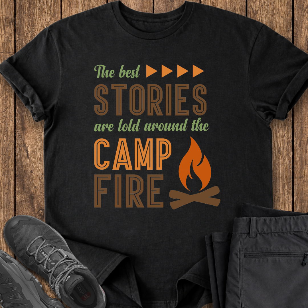 Black t-shirt with 'The best stories are told around the campfire' text and graphic on a wooden surface. camper camping camp outdoor adventure t shirt