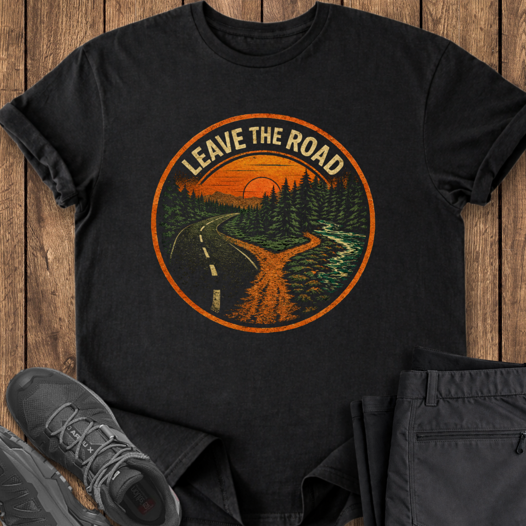 Black t-shirt with 'Leave the Road' graphic design on a wooden surface with shoes and pants. hiking t shirt