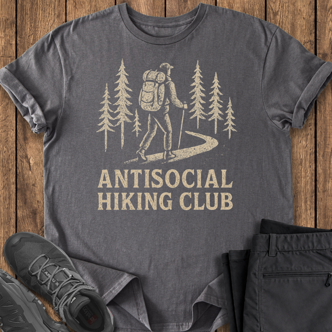 Gray t-shirt with 'Antisocial Hiking Club' design on a wooden surface with hiking shoes and pants.