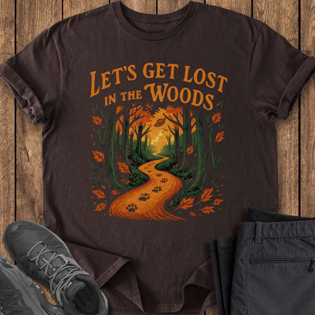 Brown t-shirt with 'Let's Get Lost in the Woods' design on a wooden surface with shoes and pants.