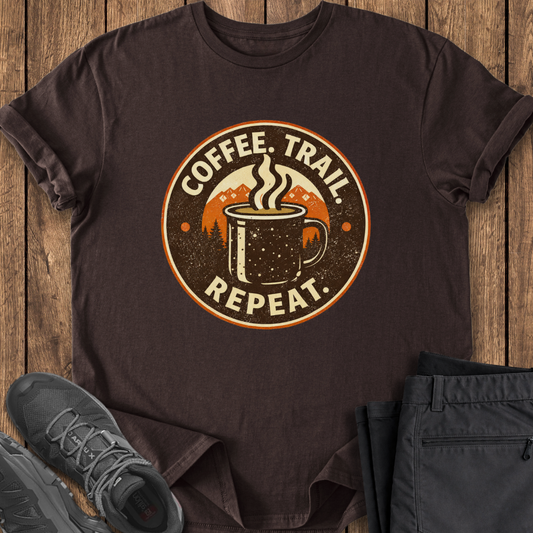 Brown t-shirt with 'Coffee. Trail. Repeat.' graphic on a wooden surface with shoes and pants. hiking tee