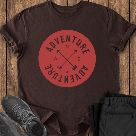 Brown t-shirt with red 'Adventure' graphic on a wooden surface with shoes and pants.