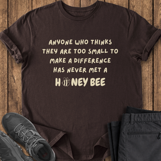 Brown t-shirt with motivational quote on a wooden surface with shoes and pants. environment conservation bee t shirt