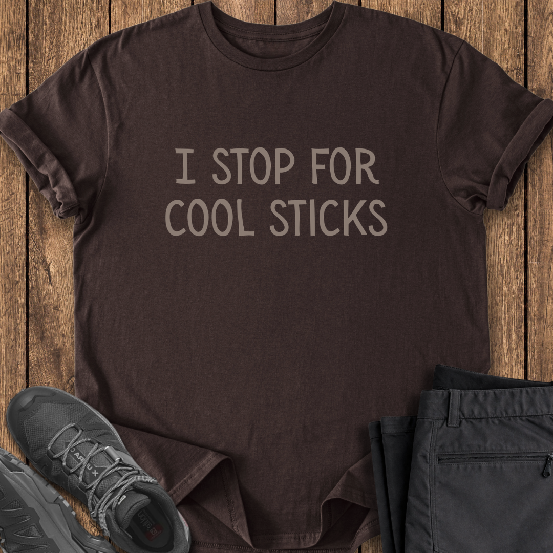 Brown t-shirt with 'I Stop for Cool Sticks' text on a wooden surface with shoes and pants. funny hiking t shirt