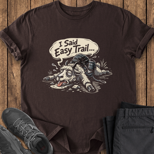 Brown t-shirt with a graphic design of a donkey and text 'I Said Easy Trail' on a wooden surface. funny goat slow hiking t shirt