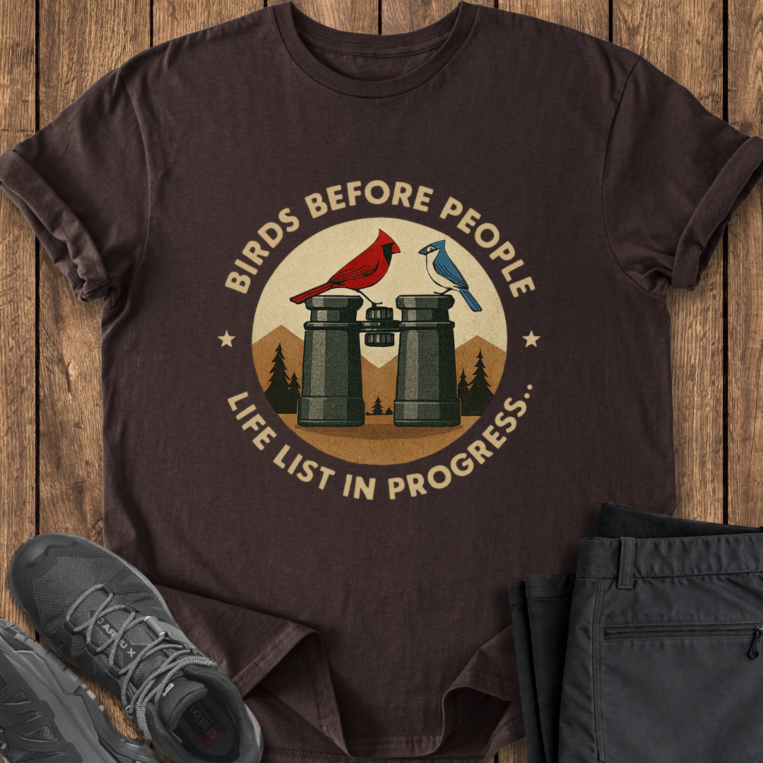 Brown t-shirt with bird-themed graphic and text on a wooden surface